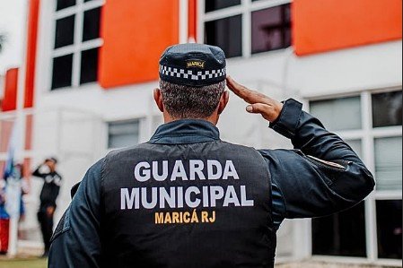 Guarda municipal de Maricá de costas, batendo continência, com a identificação da corporação nas costas do uniforme